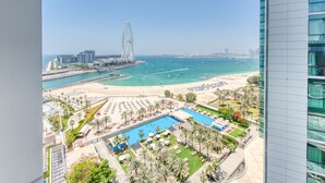 Een resort met een zwembad, strand en een reuzenrad op de achtergrond.