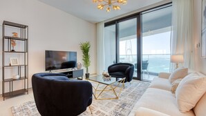 Een moderne woonkamer met een bank, twee fauteuils, een televisie en een glazen tafel.