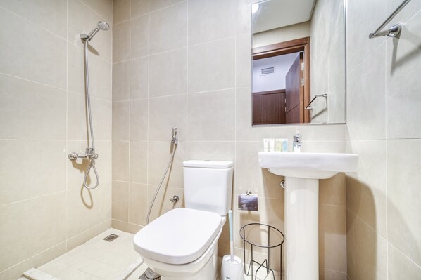 A small bathroom with a toilet, sink, and shower.
