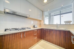 A modern kitchen with wooden cabinets, a gas stove, and a large window providing natural light.