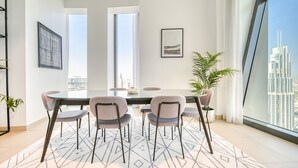 A modern dining area with a glass table, four chairs, and a geometric patterned rug. - Contemporary Apt with Burj Khalifa View (Dubai)