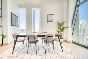 Ein moderner Essbereich mit einem Glastisch, vier Stühlen und einem Teppich mit geometrischem Muster.