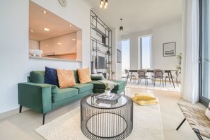 Un salon moderne avec un canapé vert, une table basse ronde et un coin repas comprenant une table et des chaises.