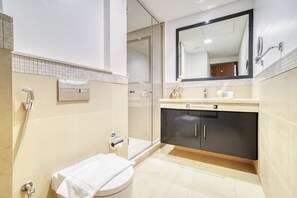 A modern bathroom with a glass shower enclosure, a toilet, a sink with a vanity, and a large mirror.