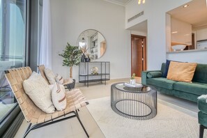 Un salon moderne avec un canapé vert, une table basse ronde et un fauteuil en osier.