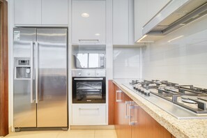 Une cuisine moderne équipée d’un réfrigérateur en acier inoxydable, d’un four encastré et d’une cuisinière à gaz.