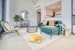 Un salon moderne avec un canapé de couleur turquoise, une table basse ronde et un fauteuil à rayures.