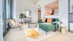 A modern living room with a green sofa, a round coffee table, and a large window. - Contemporary Apt with Burj Khalifa View (Dubai)