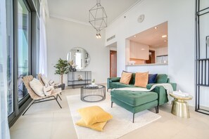 A modern living room with a green sofa, a round coffee table, and a large window.