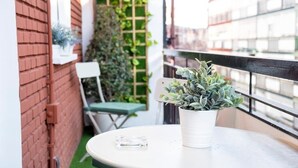 Un petit balcon avec une table ronde, un pot de fleurs et une chaise.