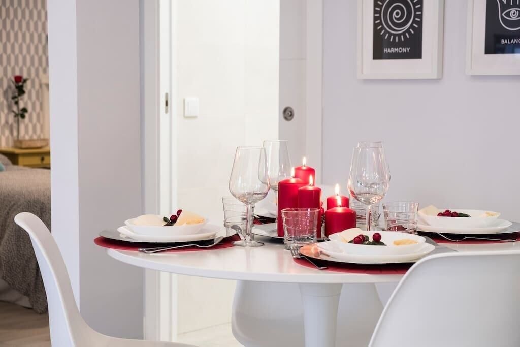 A dining table set with plates, glasses, and red candles.