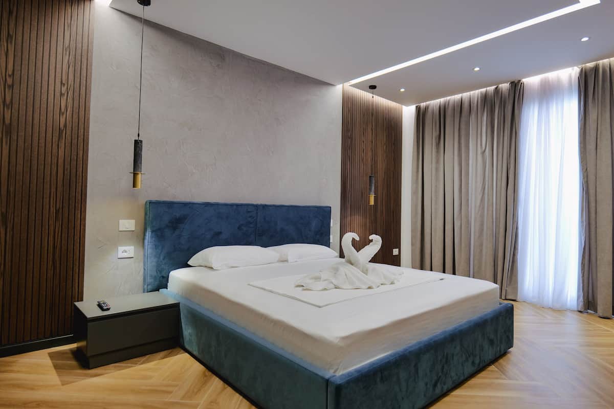 A modern bedroom with a large bed, wooden paneling, and a blue headboard.