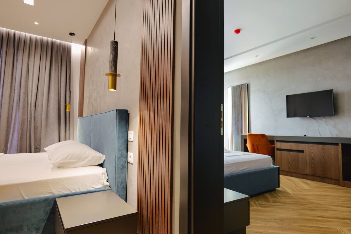 A modern hotel room with a large bed, a desk, and a television.