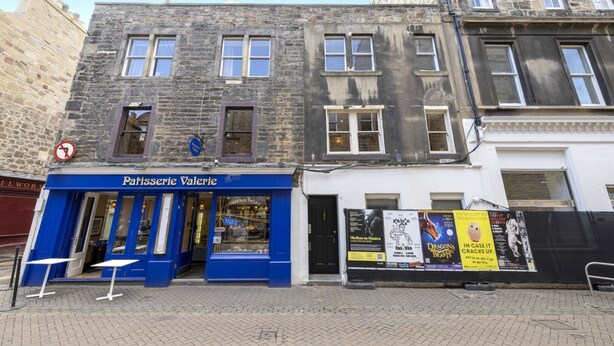 A building with a blue storefront labeled "Patisserie Valerie" and a white building with a black gate. - Modern Flat on Rose Street (Edinburgh)