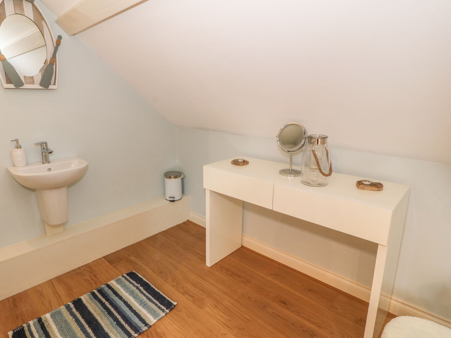 A small, clean bathroom with a white sink, mirror, and vanity.