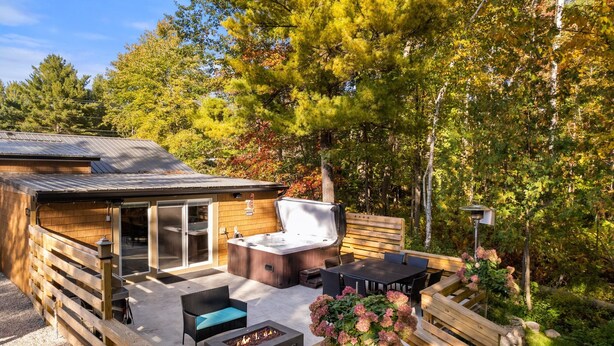 Une terrasse en bois avec un jacuzzi, des sièges d’extérieur et un foyer.