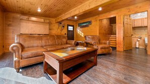 L’intérieur d’un chalet en bois, avec un canapé en cuir, des fauteuils et une table basse.