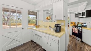 A kitchen with white cabinets, a double sink, a microwave, and a stove.