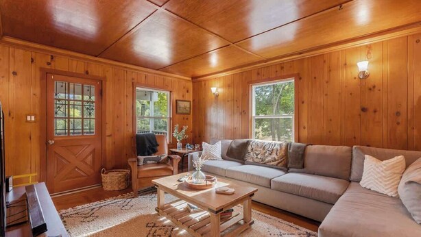 A cozy wooden interior with a sofa, coffee table, and a TV.