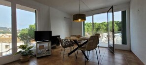 Un balcon avec une table et des chaises pour prendre les repas, un téléviseur et une plante en pot.