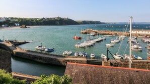 A harbor with boats docked, a stone wall, and a clear sky. - Clicketts Court (Tenby)