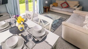 A dining area with a table set for four, a sofa, and a television. - Clicketts Court (Tenby)
