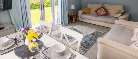 A dining area with a table set for four, a sofa, and a television.