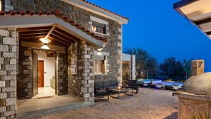 Un edificio de piedra con patio, asientos al aire libre y piscina.