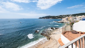 A coastal view with a beach, rocky shoreline, and buildings in the background. -  Casa Concha Apartamentos (Palafrugell)