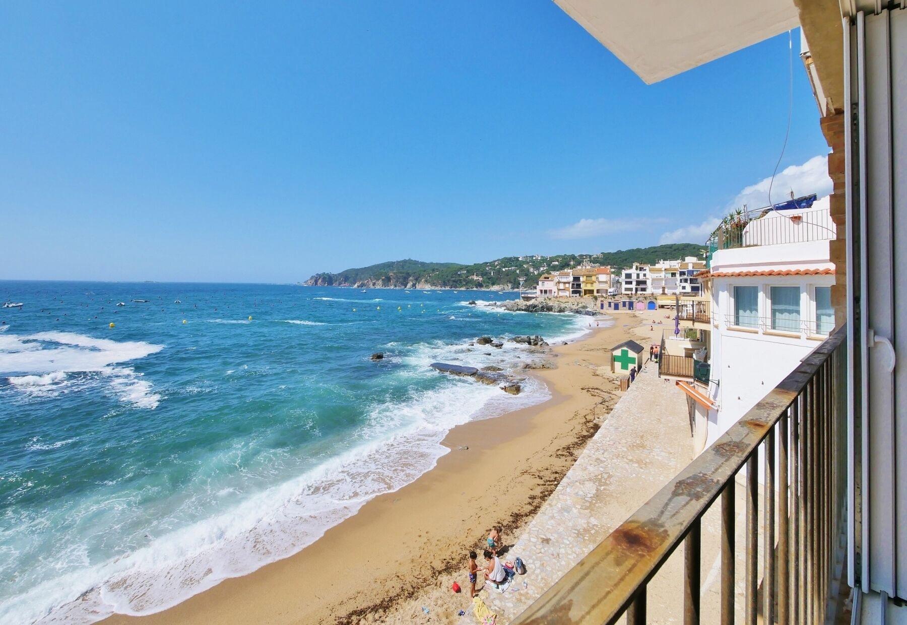 A coastal view with a beach, ocean, and buildings in the background.