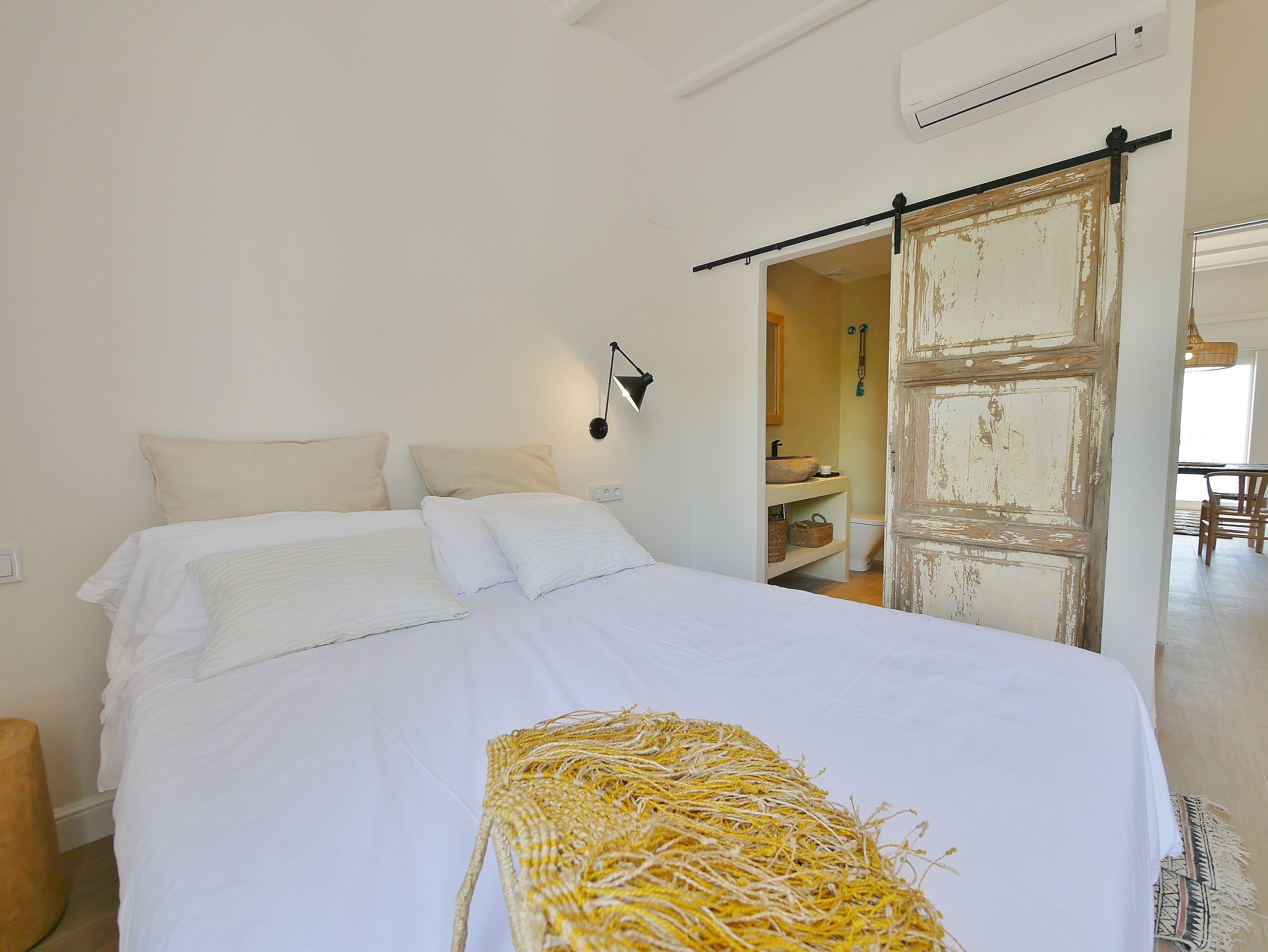 Une chambre à coucher avec un lit, une lampe de chevet, une porte rustique et une vue sur une salle de bain.