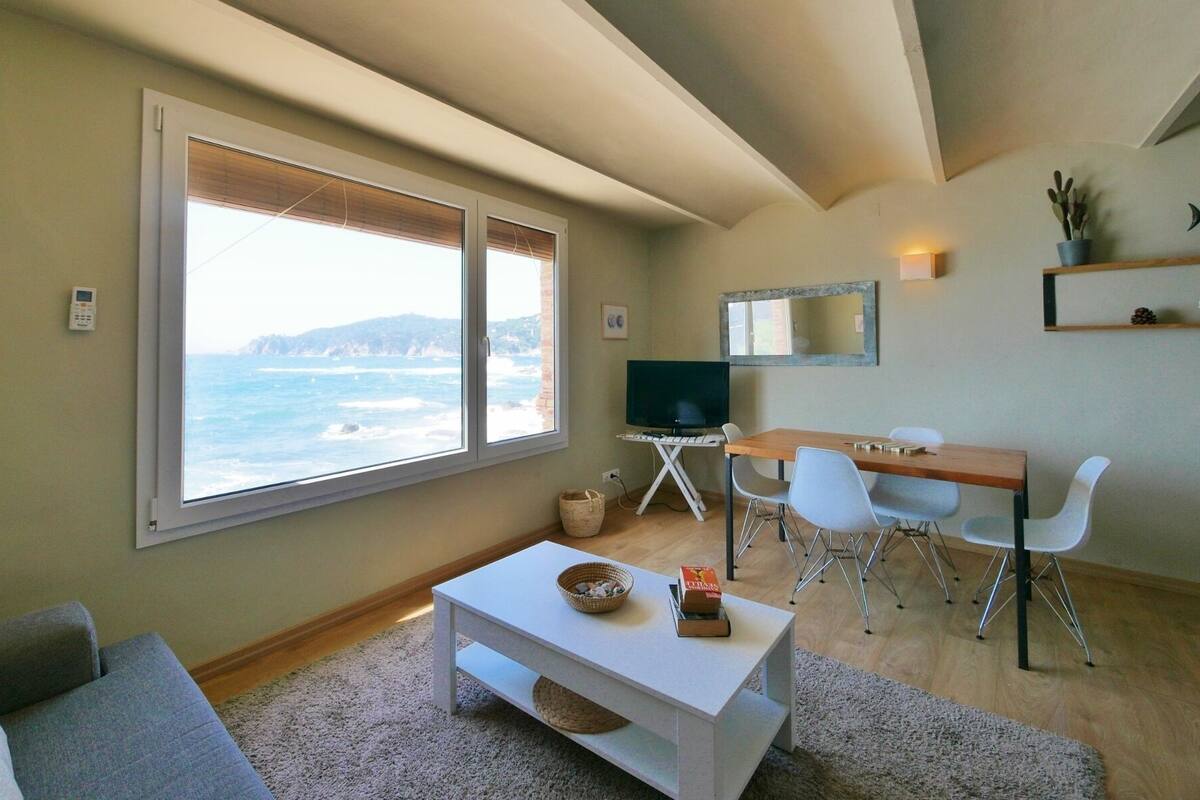 Una sala de estar con un ventanal grande, un televisor, un escritorio y un sofá.