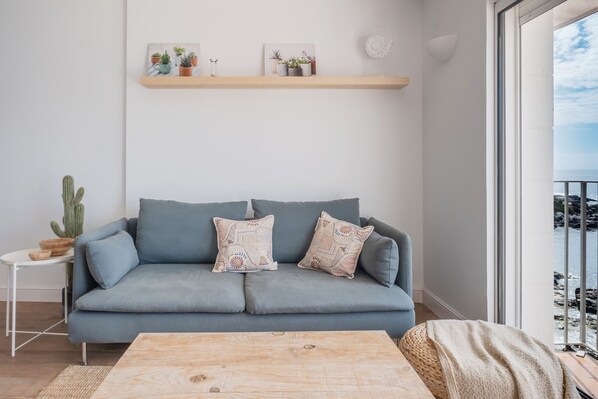 A modern living room with a grey sofa, patterned cushions, a wooden coffee table, and a cactus on a side table.