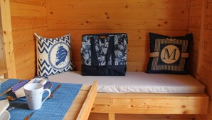 Habitació de cabana de fusta amb un llit, almoinos, una tassa i una taula petita amb coberts.