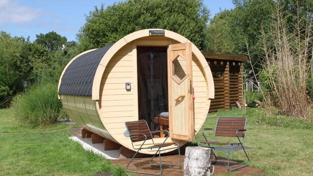 Una cabana de fusta amb façana corbada, una porta i dues cadires a l'exterior.