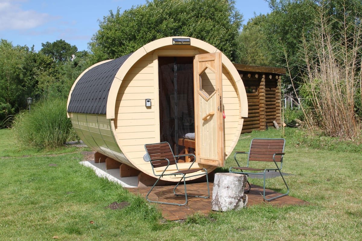 Een vakantiehuis in blokhutstijl met een gebogen gevel, een deur en twee stoelen buiten.