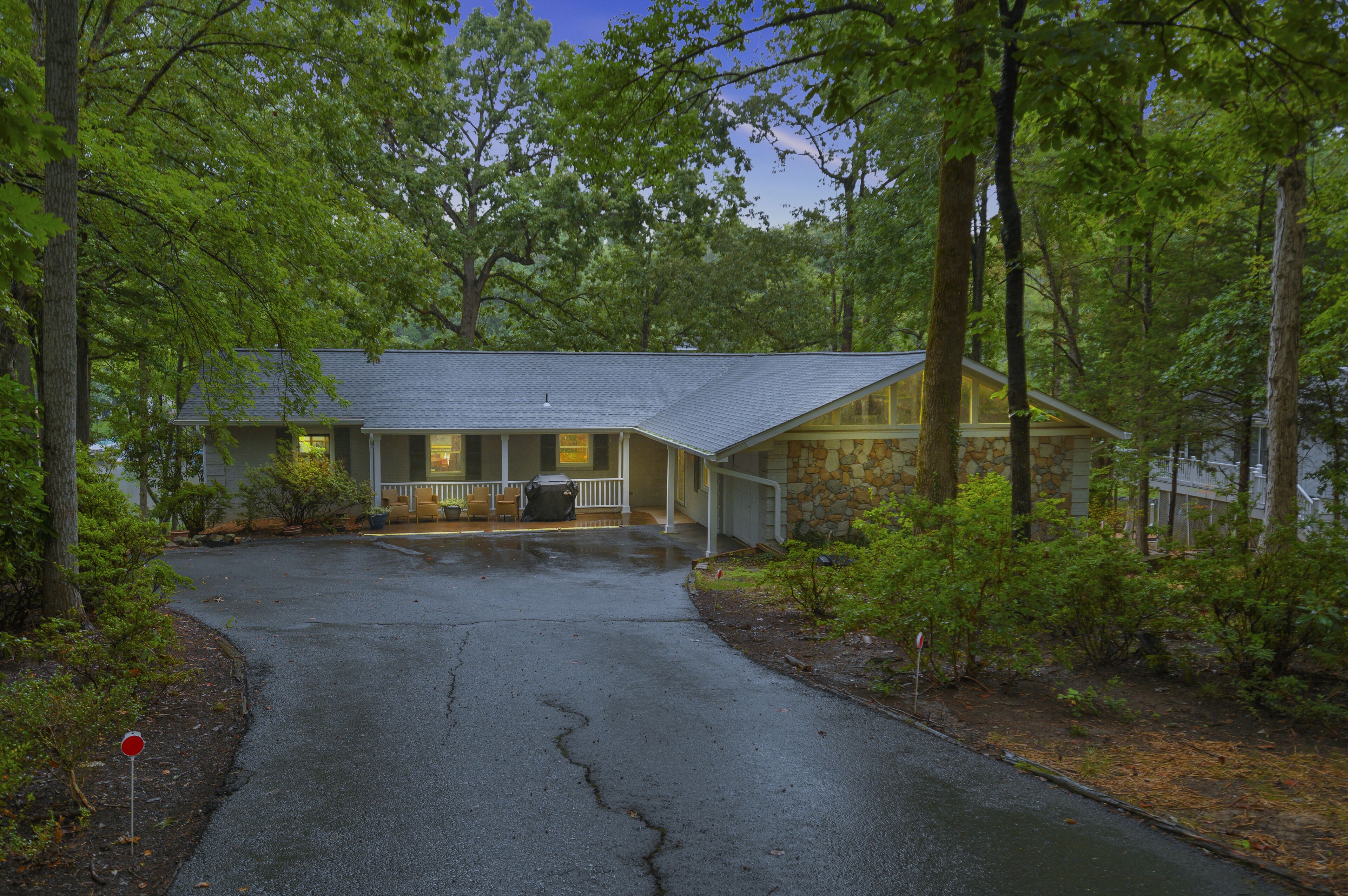 A lodge with a stone exterior, a covered porch, and a driveway leading to the entrance.