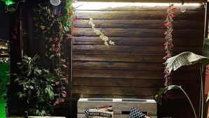A wooden wall with a bicycle-themed pillow and a bottle on a table.