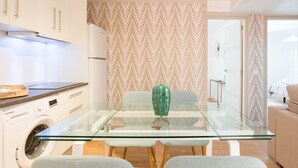 A modern kitchen with a glass dining table, a washing machine, and a patterned wallpaper. - Merced10 3E (Málaga)