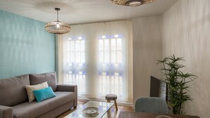 A living room with a sofa, a coffee table, a chair, and a plant. - Merced10 3E (Málaga)