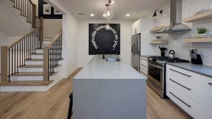 Eine moderne Küche mit einer zentralen Kochinsel, Edelstahlgeräten und einer schwarz-weißen Wand mit einem Rundmuster.