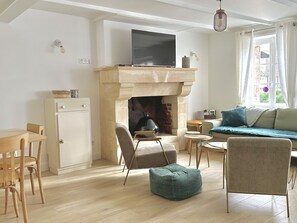 Un salon chaleureux avec une cheminée, un téléviseur et des fauteuils confortables.