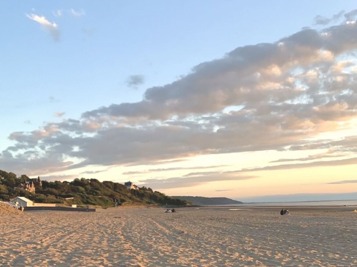 A wide beach with a clear sky and distant hills.