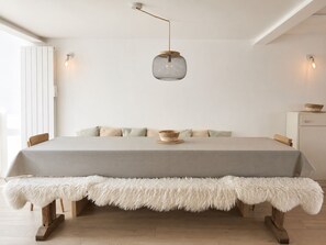 A bedroom with a bed, a fluffy bench, a hanging light fixture, and a small cabinet.