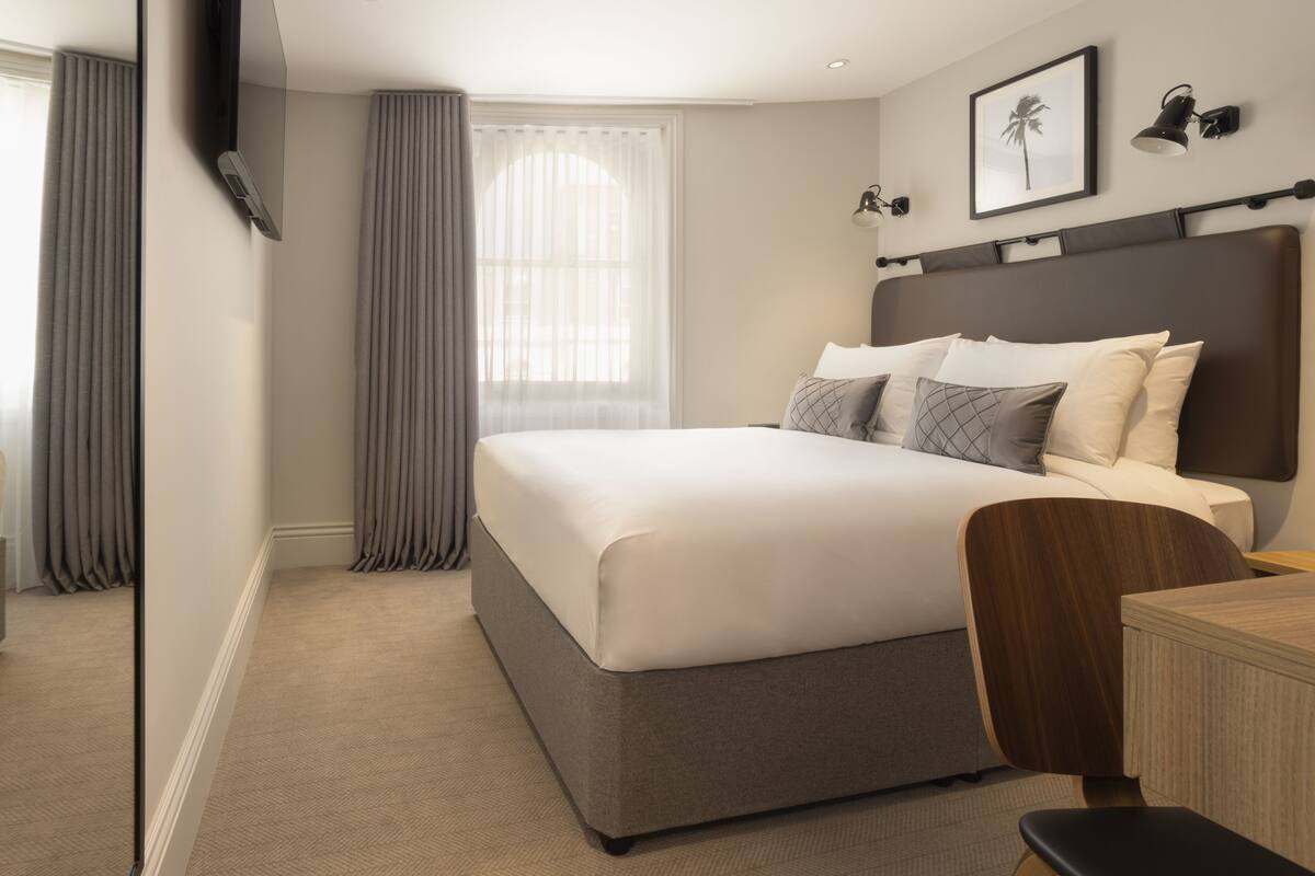 Ett modernt hotellrum med en stor säng, ett skrivbord och en stol.