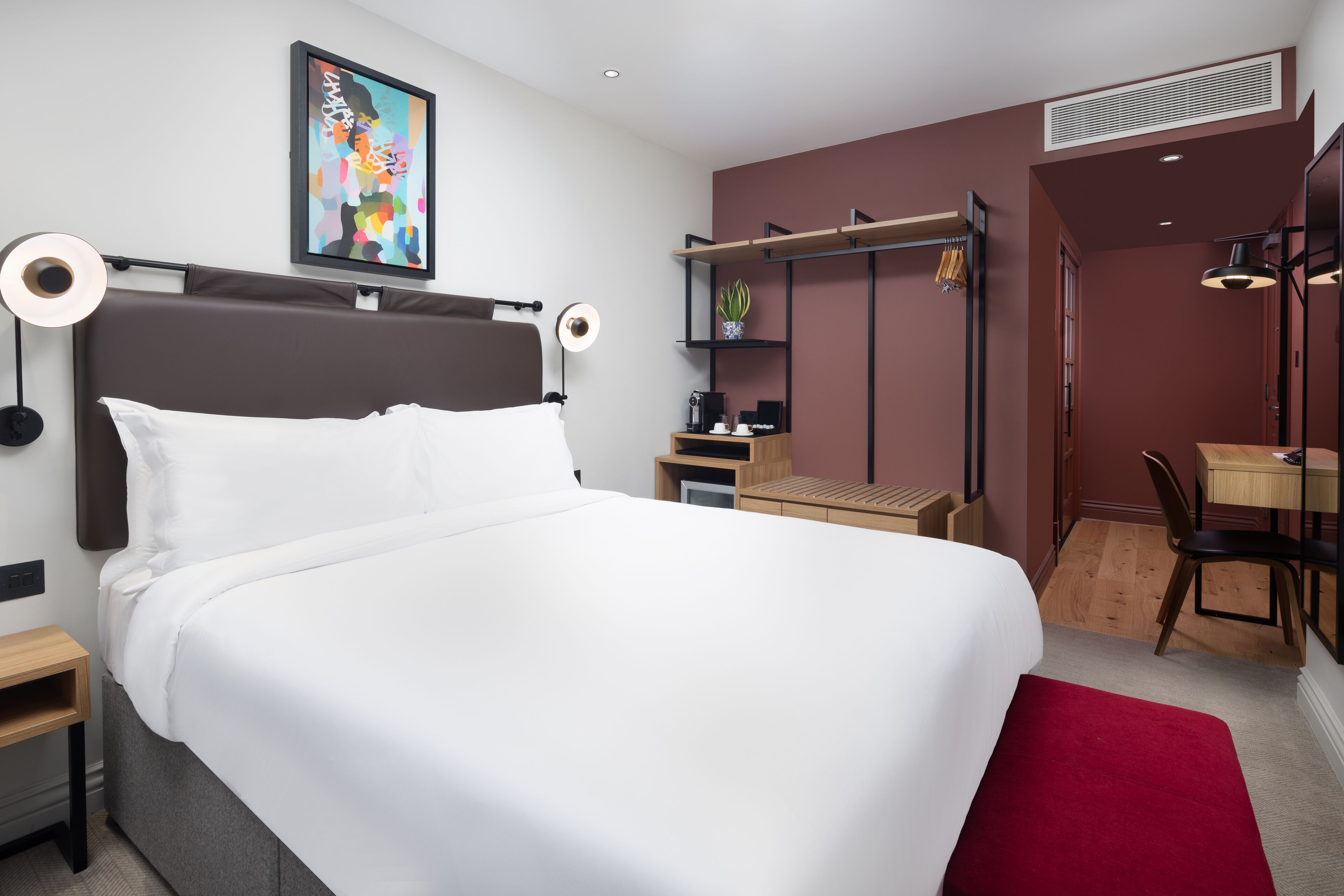Een moderne hotelkamer met een groot bed, nachtkastjes, een bureau en een stoel.
