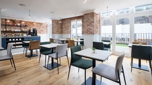 A modern cafe with brick walls, wooden floors, and a variety of seating options.