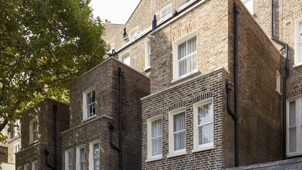 A courtyard with outdoor seating, a brick building, and a black metal fence.