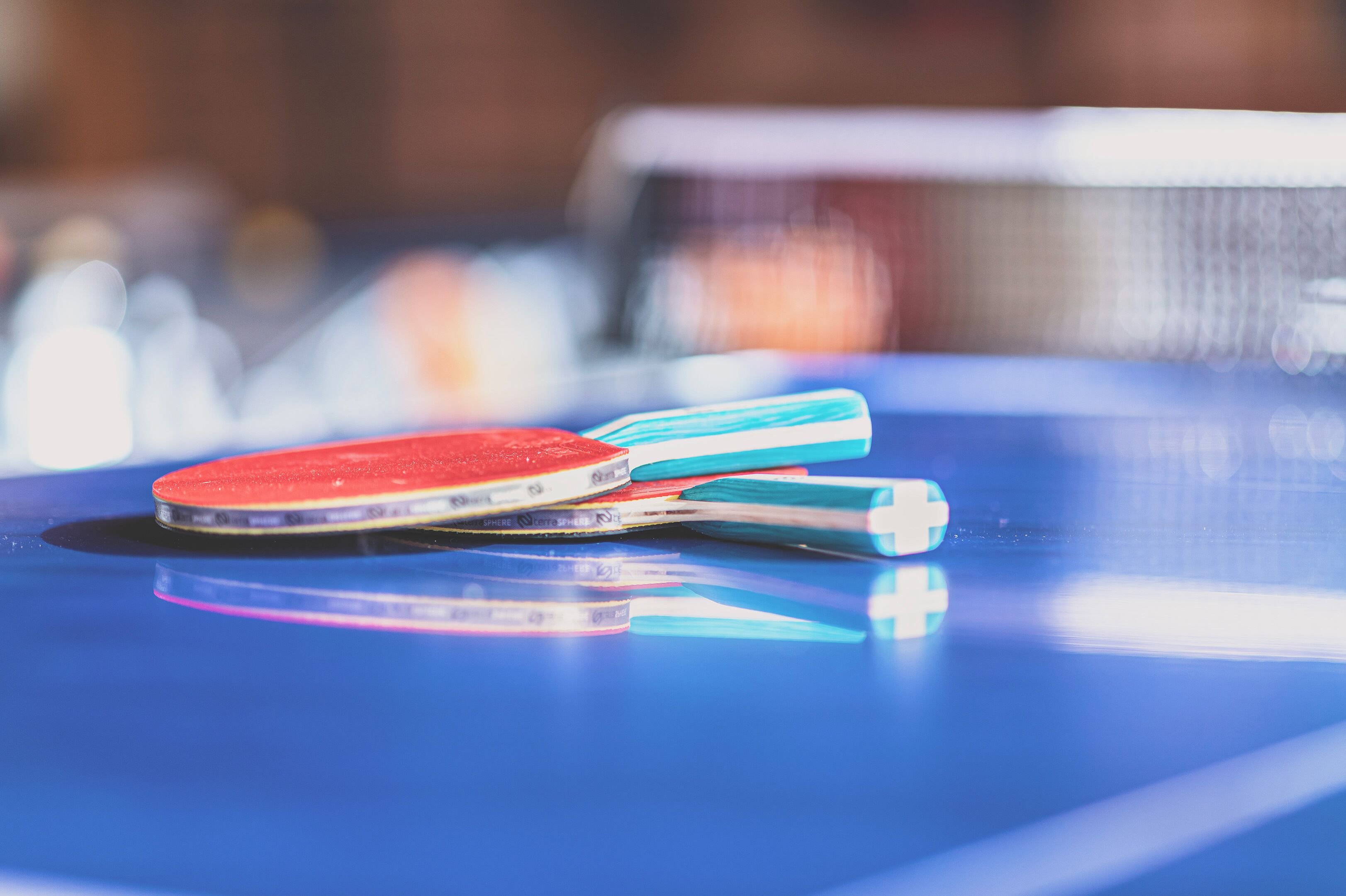 Primer plano de una mesa de ping pong con una paleta roja y azul.