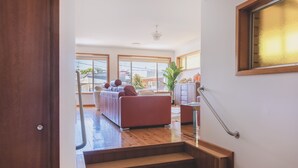 A spacious living area with a red sofa, wooden flooring, and large windows offering a view of the outside. - Vibin' Fun House 400meters (5 min walk) to D'Albora Marinas.
Outdoor Spa
 (Nelson Bay)